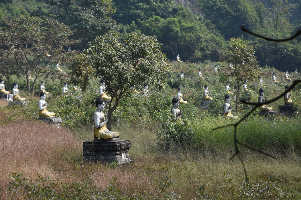 1121 Buddha statues are placed in the forrest beneath a steep mountain